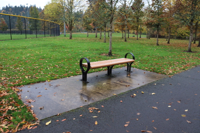 Bench with companion seating and sports field along paved trail